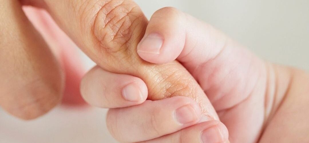 mom and baby holding finger